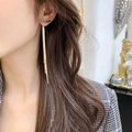 Detailed close-up of long gold fringe tassel earrings worn by a model in soft lighting - Gold Arc Snake Chain Tassel