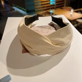 Close-up of beige PU leather headband with a twisted knot design on a display card - Beige