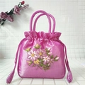 Close-up of magenta silk bucket bag featuring floral embroidery and drawstring closure - Watermelon red