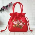 Detail of red satin bucket bag featuring intricate floral ribbon embroidery and drawstring - Red