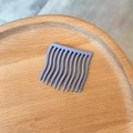 Detail eines matt lavendelfarbenen 11-Zahn-Wellenhaarkamms auf einer Holzoberfläche - Matter Kunststoff / Lavendel