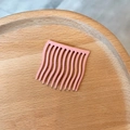 Matter hellrosa Haarkamm mit gewellten Zinken auf einem Holztablett zum Styling - Matter Kunststoff / Hellrosa