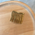 Makro-Detail von 10-Zahn Gold Metall Haarkamm mit Wellenzähnen auf Holztablett - Metalllegierung / Gold