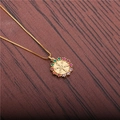 Collar dorado con colgante de timón de circonitas sobre fondo de madera oscura - Cadena de Caja Timón
