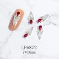 Macro view of 3D V-shaped nail art charms with red teardrop stones and silver settings - Silver Red Gem Style (6872)