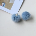 Close-up of soft light blue plush ball pendants with golden metal rings for DIY jewelry - Blue