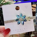 Blue crystal flower hair clip with gold plating and white rhinestones on jewelry card - Crystal Plum Flower Blue Clip
