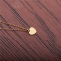 Polished gold heart pendant necklace in stainless steel on a rustic wood background - Gold