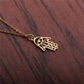 Goldene Hamsa-Halskette mit Evil Eye-Anhänger auf braunem strukturiertem Hintergrund - Gold