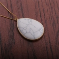 Macro shot of a teardrop-shaped white marble pendant on a delicate gold chain - White Turquoise Water Drop