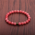 Close-up of pink striped beads and green cylinder accent on a wooden surface - Pink Striped Stone