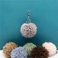 Close-up detail of cute curly plush pompom keychains in various soft pastel colors - 1 Piece / Gray