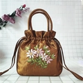 Detail of vintage bronze satin bag featuring intricate ribbon embroidery flowers and drawstrings - Coffee