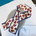 Detailed macro view of cream floral satin ribbon with navy trim on a display tray - Beige Red Floral