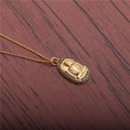 Goldene Buddha-Halskette mit schwarzen Zirkon-Steinen auf dunklem Holzhintergrund - O-Kette Buddha-Gold