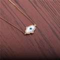 Gouden Hamsa Hand ketting met blauwe boze oog hanger op donkerhouten achtergrond - Goud Boze Oog Hamsa Hand
