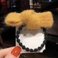 Elastico per capelli con fiocco di peluche giallo su cartoncino bianco tenuto in mano - Linea di Punti Fiocco-Giallo