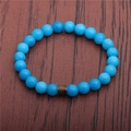 Detailed top view of beaded bracelet with light blue round beads on dark wood background - Sky Blue Stone