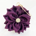 Close-up of a purple silk evening bag with handcrafted fabric flower and rhinestone detail - Deep purple