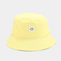 Detailed close-up of a light yellow cotton bucket hat with a white square smiley face patch - Yellow
