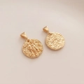 Vista macro del ciondolo Gemelli placcato oro 14K con dettagli a rilievo e trama ondulata - Gemelli