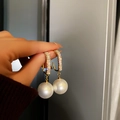Dettaglio macro di orecchini a cerchio dorati con zirconi lucenti e grandi perle bianche - Bianco (Perno Argento)