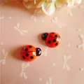 Close-up of orange resin ladybug charms for DIY hair clips and phone case decor - Red