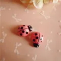 Close-up of pink resin ladybug charms with black spots for DIY hair clips and crafts - Rose Red