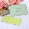 Light green envelope case and yellow silver polishing cloth on a soft white plush surface - Silver Polishing Cloth