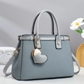 Détail du sac à main gris tressé avec breloque cœur et poignées en cuir lisse - Bleu