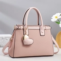 Detail of light pink woven handbag showing elegant heart charm and adjustable strap - Pink