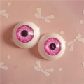 Macro detail of 20mm round pink BJD doll eyes with spiral iris pattern for DIY crafts - Pink