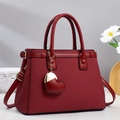 Détail du sac à main rouge avec breloque cœur dorée et bandoulière en cuir réglable - Bordeaux