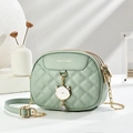Detail shot of mint green quilted bag with cat pendant and gold chain strap - Green