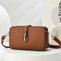 Brown litchi grain leather crossbody bag with double zippers on a stone pedestal - Earthy Yellow