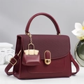 Elegant wine red handbag with quilted panel and gold ring lock on a premium pedestal - Red
