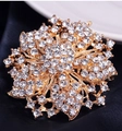 Luxurious gold crystal flower brooch with shimmering rhinestones on dark fabric - Gold White
