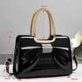 Dettaglio borsa in pelle verniciata nera con grande fiocco di strass e manico dorato - Nero