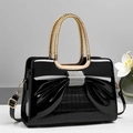 Close-up of black patent leather bag with rhinestone bow and gold woven handle details - Black