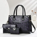 Detailed macro view of a 3-piece shiny black tote set with purple floral relief and gold hardware - Purple