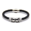 Detail of black braided leather bracelet featuring silver skull beads and magnetic clasp - White K + Black Leather