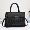 Detail of black quilted handbag featuring embossed floral patterns and gold metal lock - Black
