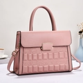Close-up of pink embossed handbag featuring square relief pattern and gold metal buckle - Pink