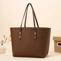 Close-up of dark brown pebble leather tote bag with silver rivets and slim shoulder straps - Coffee