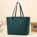 Close-up of dark green tote bag featuring lychee texture leather and silver rivet details - Green