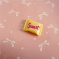 Macro detail of yellow resin candy accessory with Sweet text for DIY crafts - Sweet Lettering / Milk Yellow