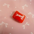 Macro detail of red candy-shaped resin charm with Sweet text for DIY crafts - Sweet Lettering / Red