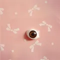 Detailed view of 10x14mm brown acrylic doll eyes with intricate iris texture on pink card - Dark Brown