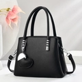 Black litchi grain leather tote bag with heart charm and silver hardware on white background - Black