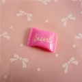 Close-up of pink resin candy charm with Sweet lettering for DIY crafts and hair accessories - Sweet Lettering / Rose Red